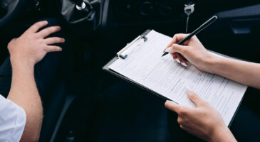 Une femme en train de compl&eacute;ter un contrat d&rsquo;assurance automobile